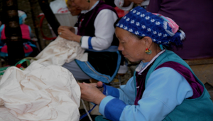 雲南白族老婦人正在縫染布的圖案縮圖